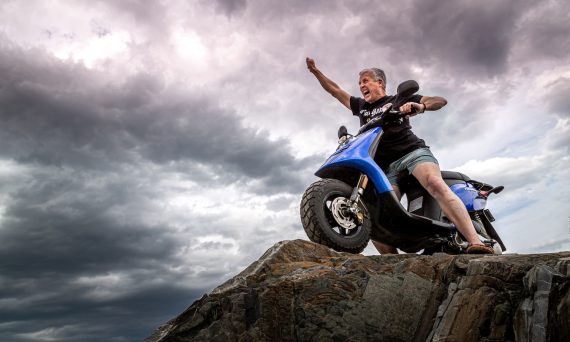 man in black jacket and blue denim jeans riding blue and white motorcycle